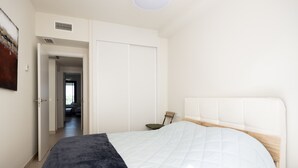 A bedroom with a bed, a wardrobe, and a door leading to another room. - Horizonte Benalmádena - Brand-New 3-Bedroom Apartment (Benalmádena)