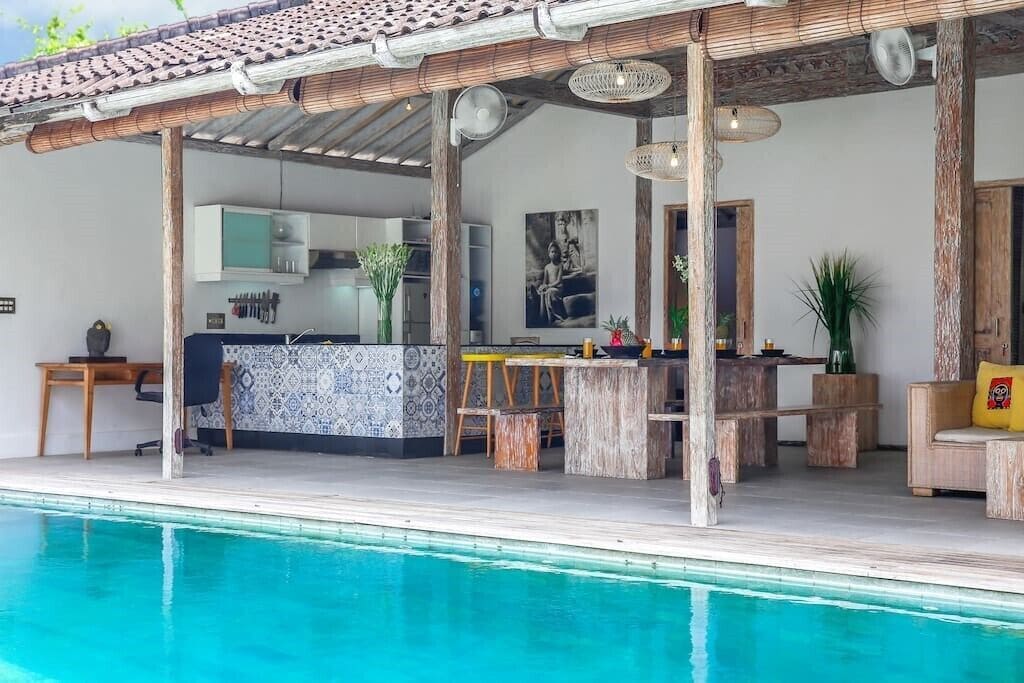 Ein Poolbereich mit Bar, Sitzgelegenheiten und einer Küche.