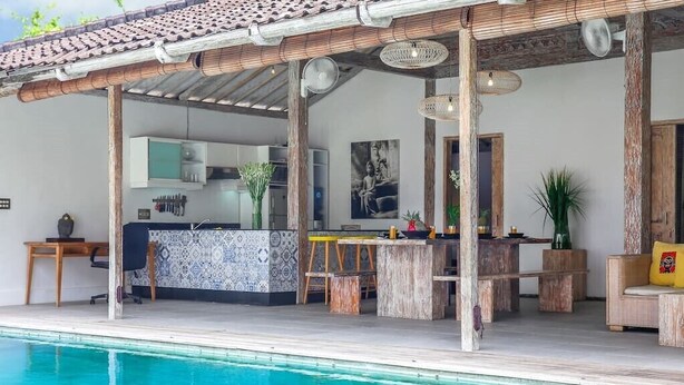 Zona de piscina con bar, asientos y cocina.