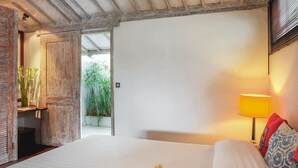 Un dormitorio con cama, mesita de noche, lámpara y vistas al exterior.