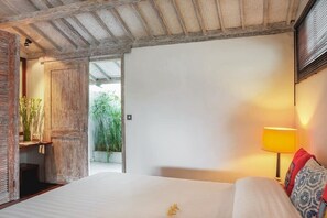 Ein Schlafzimmer mit einem Bett, einem Nachttisch, einer Lampe und Blick auf Grünfläche draußen.