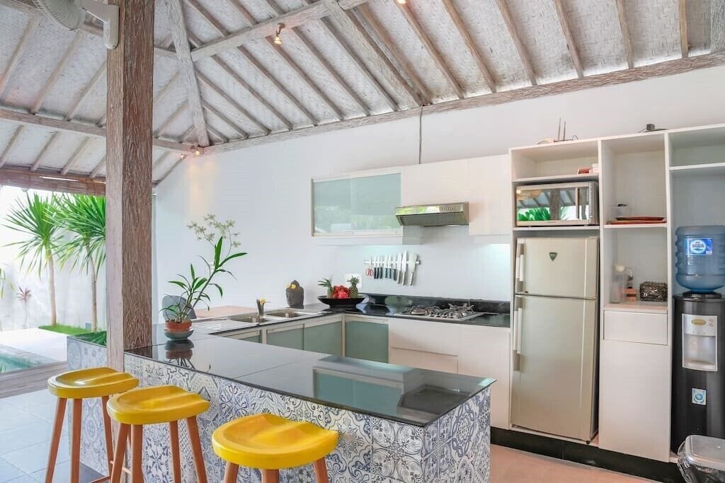 Une cuisine moderne dotée d’un îlot central, de tabourets de bar, d’un réfrigérateur et d’un distributeur d’eau.