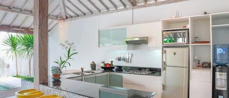 Una cocina moderna con una isla central, taburetes de bar, un refrigerador y un dispensador de agua.