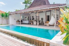 Ein Poolbereich mit überdachter Sitzgelegenheit, einem Schwimmbecken und einer Terrasse mit Pflanzen.