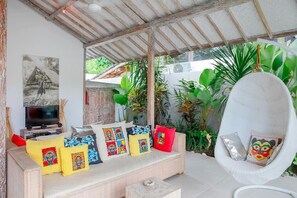 A cozy living area with a sofa, cushions, a hanging chair, and a television.