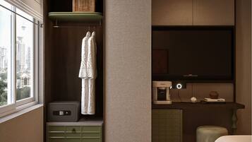 A modern hotel room with a large window, a built-in wardrobe, a flat-screen TV, a minibar, and a bed.