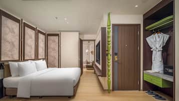 A hotel room with a bed, wardrobe, and a green decorative pillar.