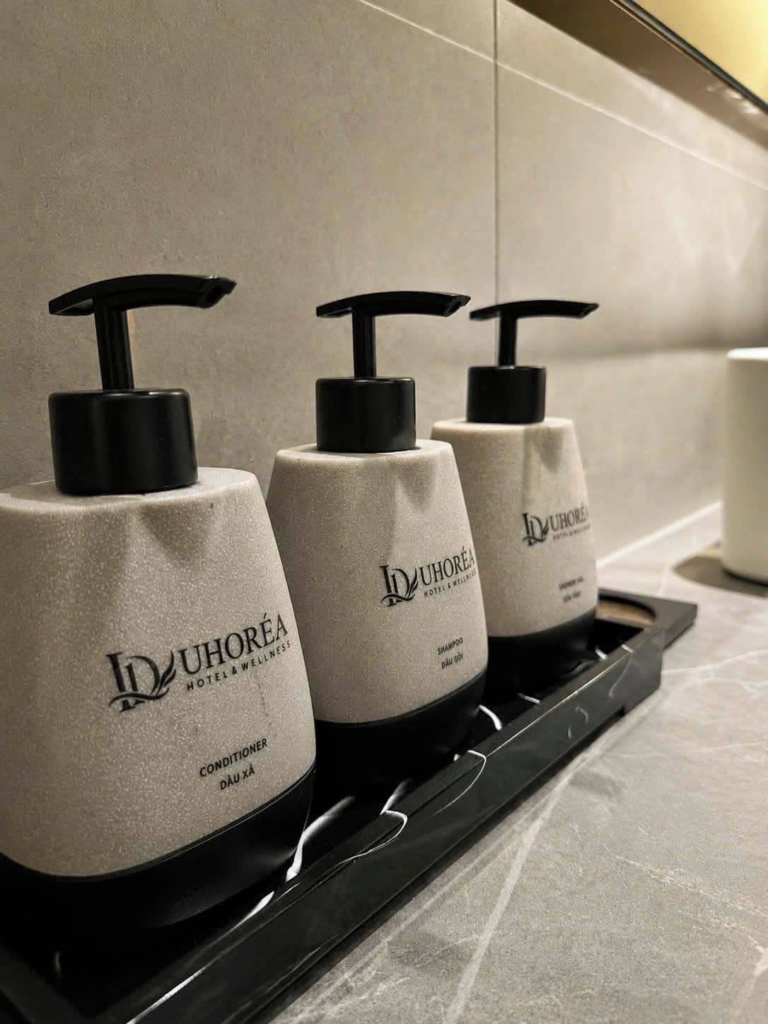 Three bottles of shampoo on a tray in a hotel bathroom.