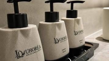 Three bottles of shampoo on a tray in a hotel bathroom.