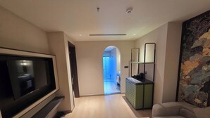 A modern living room with a flat-screen TV, a sofa, and a coffee table. - DUHORÉA hotel and wellness (Hanoi)