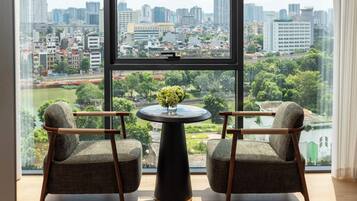 A room with two chairs facing a large window overlooking a cityscape and a river.