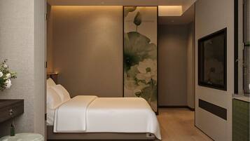 Une chambre à coucher moderne avec un lit, une table de chevet, un téléviseur fixé au mur et une grande œuvre d’art à motifs floraux.