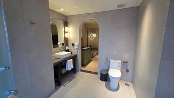 A modern bathroom with a large mirror, a sink, a toilet, and a shower area.