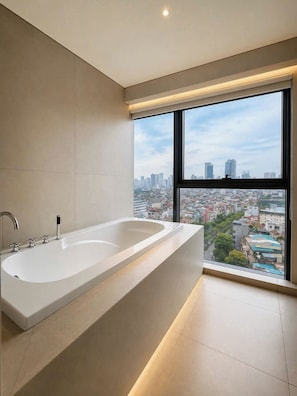 Un baño moderno con una bañera grande y un ventanal con vistas a la ciudad.