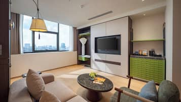 A modern living room with a sofa, armchair, coffee table, and a TV mounted on the wall.