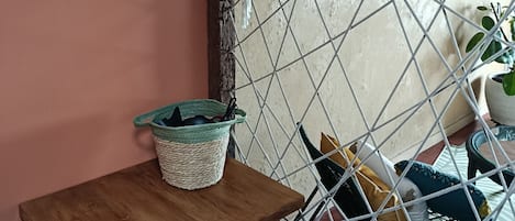 Une pièce avec une table en bois, un miroir, un panier en osier, une chaise en métal et un hamac.