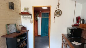 Une cuisine de taille réduite, avec une étagère en bois, un luminaire suspendu et une horloge au mur.