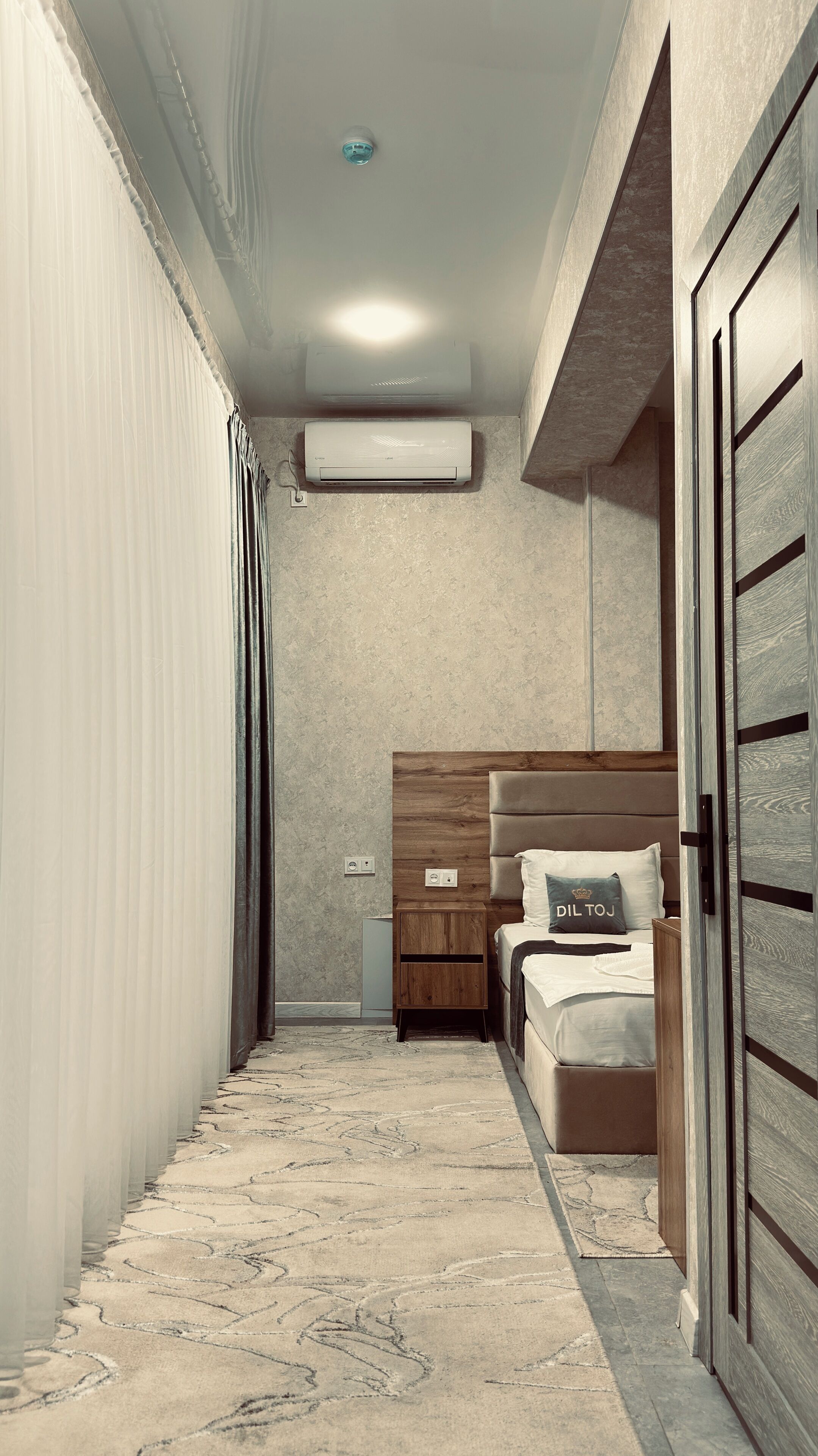 A bedroom with a bed, bedside table, and a wall-mounted air conditioner.
