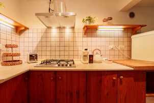 Una cocina con estufa a gas, tostadora, hervidor y armarios de madera.
