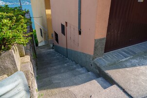 Unos escalones de piedra conducen a un edificio con una puerta marrón y una ventana con persiana metálica.