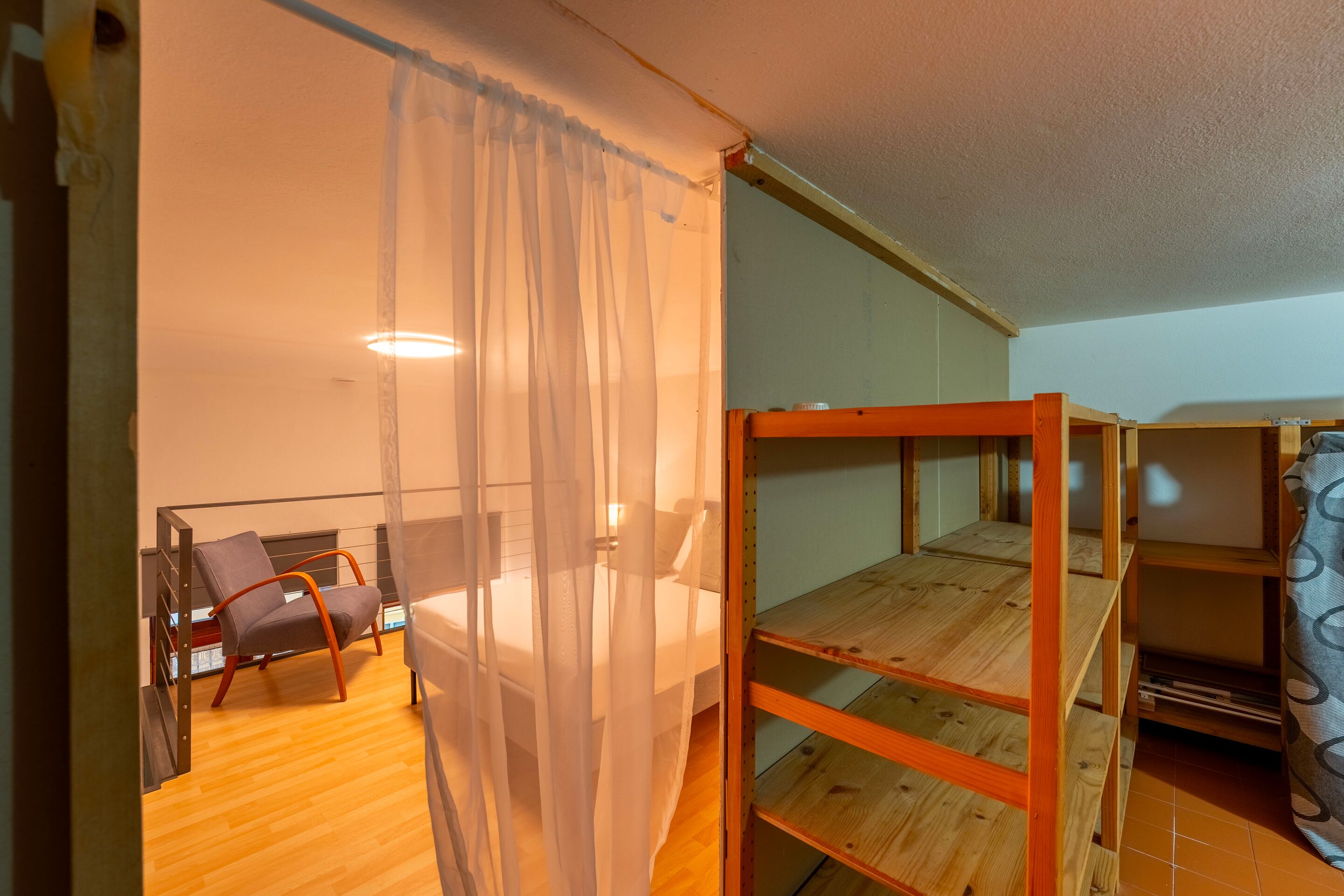 Une chambre avec un lit superposé, une chaise, une table et un rideau.