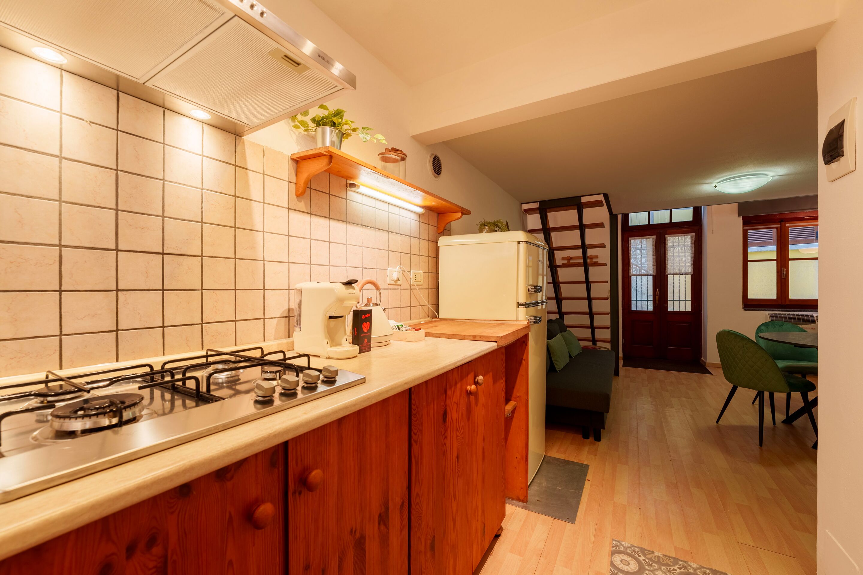 A kitchen with a gas stove, a coffee maker, and a refrigerator.