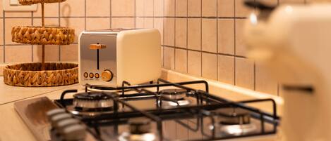 Eine Küche mit Gasherd, Toaster und einem gewebten Korb auf der Arbeitsfläche.