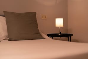 Ein Bett mit Kissen und einem Nachttisch mit Lampe.