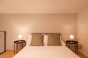 A hotel room with a bed, two bedside tables with lamps, a wooden floor, and a wall-mounted light switch. - Casa Alborella by Wonderful Italy (Colonno)