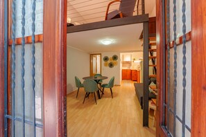 An open wooden door leading to a dining area with a round table and chairs, a staircase, and a kitchen in the background. - Casa Alborella by Wonderful Italy (Colonno)