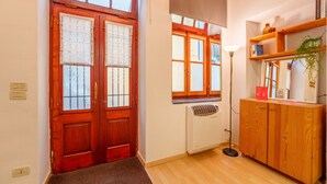 Un pasillo con una puerta de madera, un radiador, una lámpara de pie y un mueble de madera con una planta.