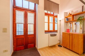 Ein Flur mit Holztür, Heizkörper, Stehlampe und einem Holzschrank mit Pflanze.