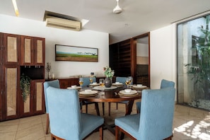 A dining area with a round table set for four, surrounded by blue upholstered chairs. - Staymaster Belamia•3BR•Private Pool (Parra)