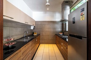 A modern kitchen with a stainless steel refrigerator, a double sink, and wooden cabinets. - Staymaster Belamia•3BR•Private Pool (Parra)
