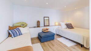 Ein Zimmer mit zwei Betten, einem kleinen Tisch, einem Spiegel und einer Wandleuchte.