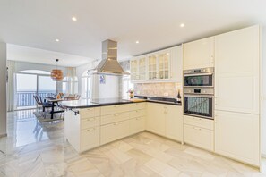 A modern kitchen with a central island, stainless steel appliances, and a view to a balcony. - Villa Mamma Mia, Luxury Villa with Panoramic Sea Views (Salobreña)