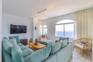 A modern living room with a sofa set, a television, a wooden coffee table, and a view of the sea through large windows. - Villa Mamma Mia, Luxury Villa with Panoramic Sea Views (Salobreña)