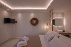 Et moderne hotelværelse med seng, fjernsyn, et spejl på væggen og et natbord med vask.
