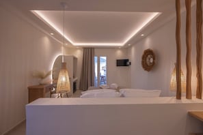 A modern bedroom with a large bed, bedside tables, a desk, and a TV. - GuVer Luxury Suites (Naxos)