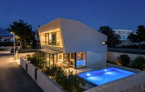 A modern two-story house with a swimming pool, glass walls, and outdoor seating. - Gorgeous home in Novalja (Novalja)