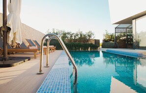 A swimming pool with a metal ladder, lounge chairs, and a tiled deck. - Gorgeous home in Novalja (Novalja)