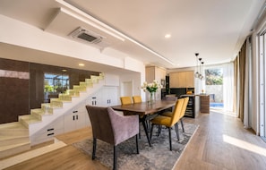 A modern kitchen with a dining area, wooden staircase, and large windows. - Gorgeous home in Novalja (Novalja)