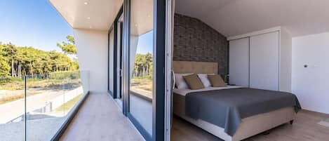 A bedroom with a large bed, a view of the outdoors, and a modern design.