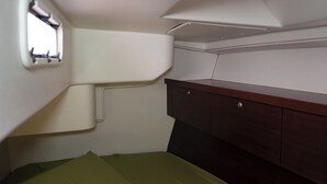 Une petite pièce comprenant un lit, un petit meuble et un luminaire fixé au mur.