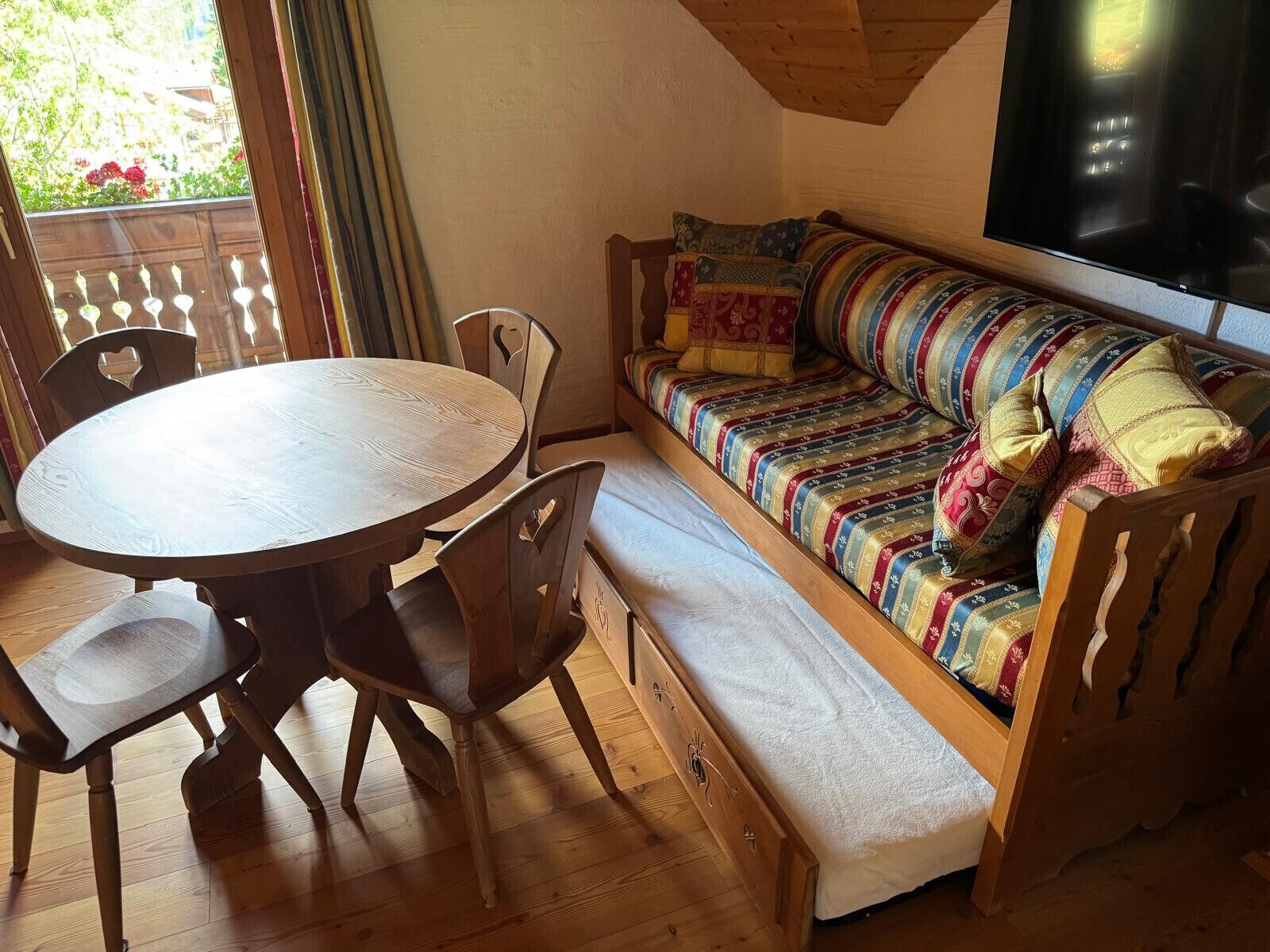 Una habitación acogedora con un banco de madera, una mesa redonda de madera y sillas.