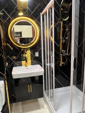 A bathroom with a white sink, a gold-framed mirror, and a glass-enclosed shower. - Modern Studio Apartment With Stunning Red Sea Views (Hurghada)