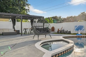 Um quintal com piscina redonda, cadeira suspensa, varanda coberta e um tabuleiro de xadrez.