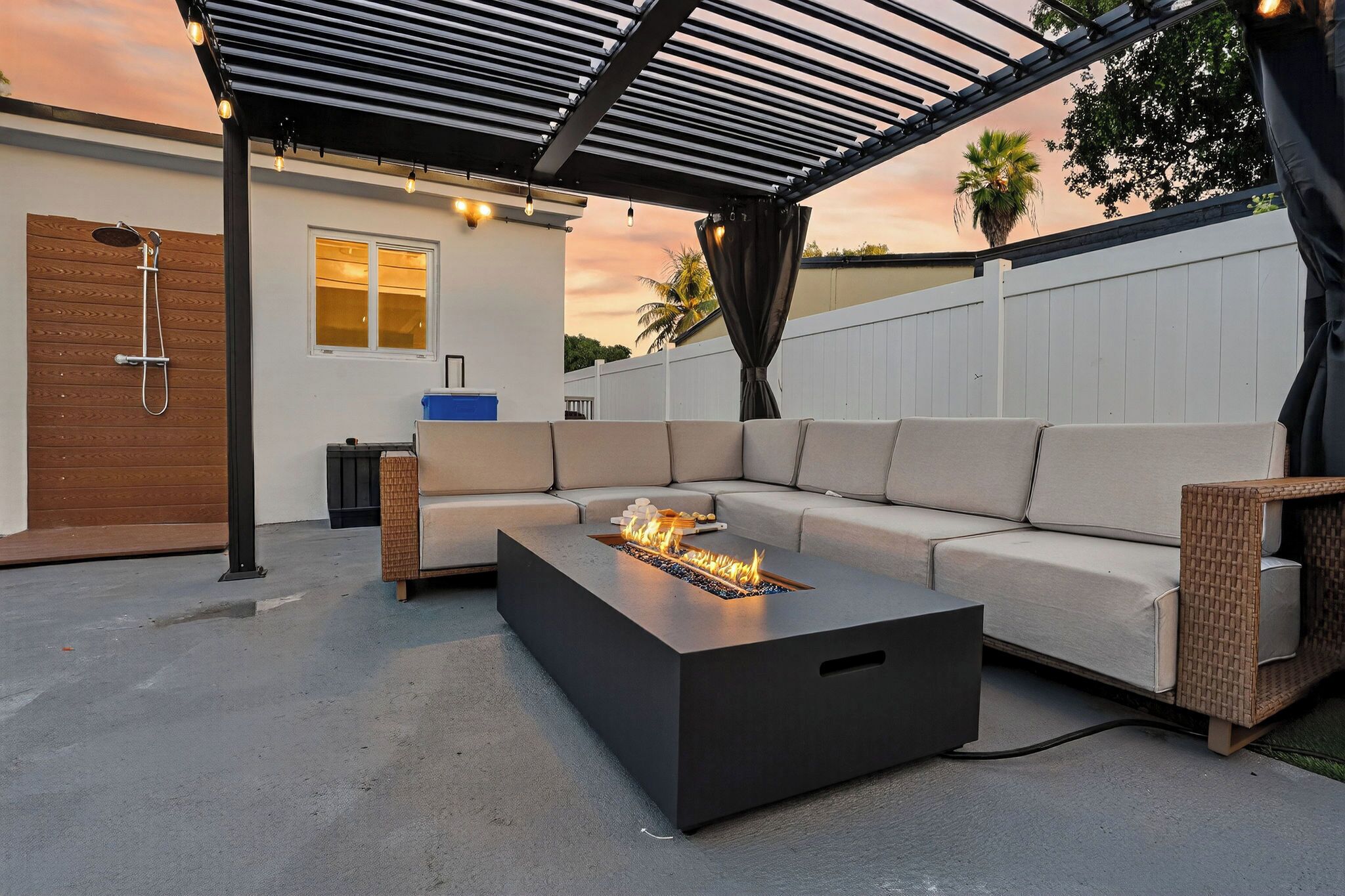 A modern outdoor living space with a fire pit, a covered seating area, and a patio.