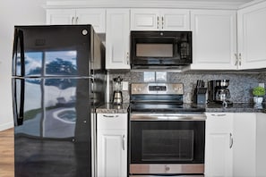 Uma cozinha moderna com eletrodomésticos de aço inoxidável, incluindo geladeira, micro-ondas e forno.
