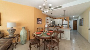 A dining area with a round table, chairs, a vase, and a lamp. - Sonoran Spa E-408 – Inviting Oceanview Condo with Relaxing Coastal Vibes (Puerto Peñasco)